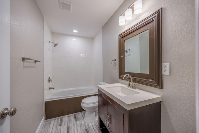 full bathroom with vanity, tiled shower / bath combo, hardwood / wood-style flooring, and toilet