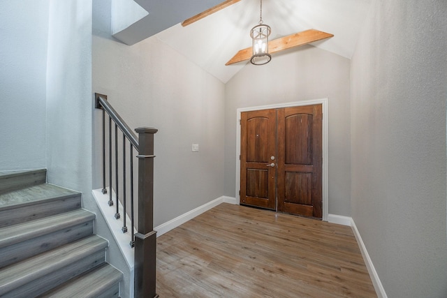 foyer entrance with hardwood / wood-style floors and vaulted ceiling with beams