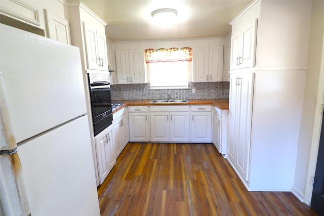 kitchen with dark hardwood / wood-style flooring, sink, white cabinets, white fridge, and black oven