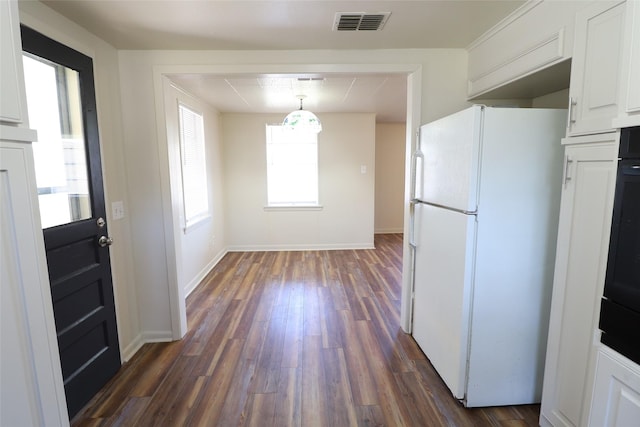 kitchen with white cabinets, decorative light fixtures, white fridge, and dark hardwood / wood-style floors