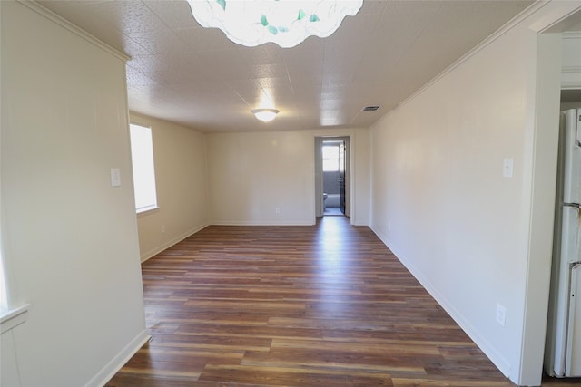 empty room featuring dark wood-type flooring and ornamental molding