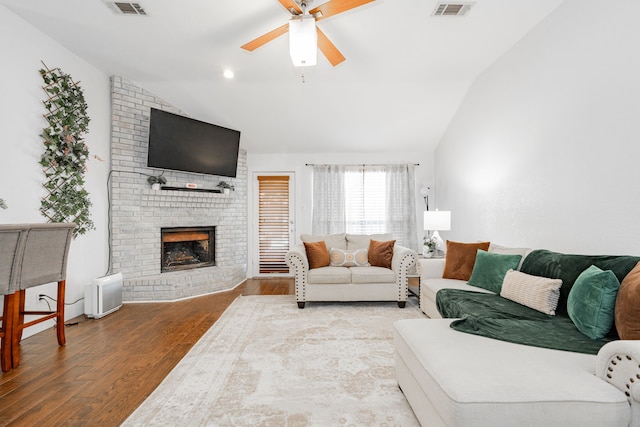 living room with a brick fireplace, ceiling fan, wood-type flooring, and vaulted ceiling