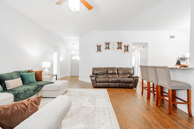 living room featuring ceiling fan, vaulted ceiling, and light wood-type flooring