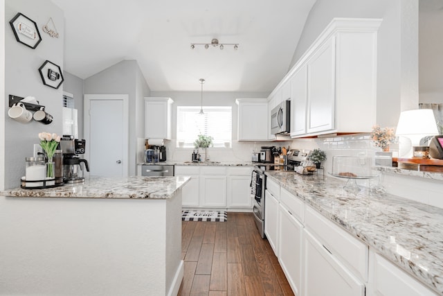 kitchen featuring appliances with stainless steel finishes, tasteful backsplash, vaulted ceiling, dark wood-type flooring, and white cabinetry