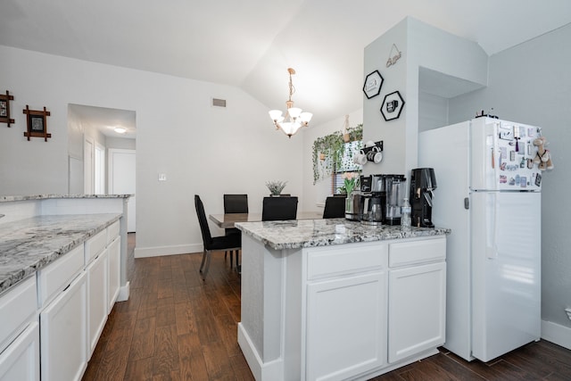 kitchen with white cabinetry, light stone counters, dark hardwood / wood-style floors, white refrigerator, and decorative light fixtures