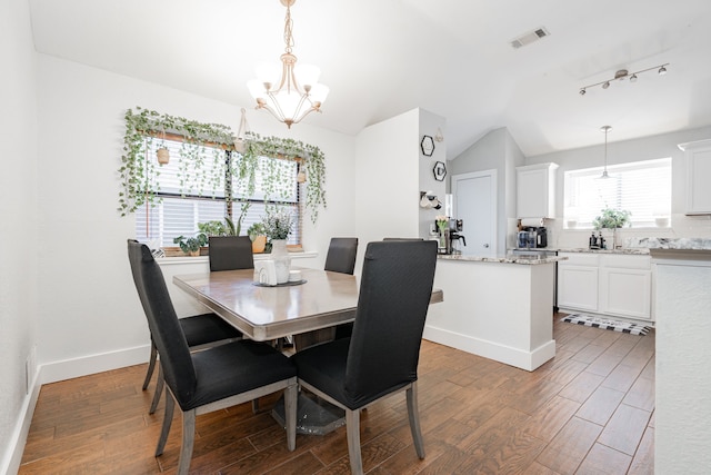 dining space with hardwood / wood-style floors, vaulted ceiling, and a notable chandelier