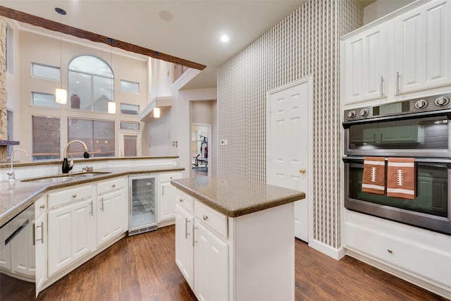 kitchen featuring white cabinetry, sink, beverage cooler, pendant lighting, and appliances with stainless steel finishes