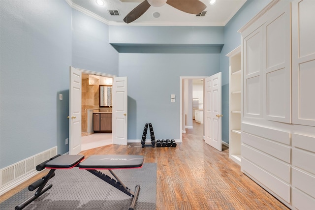 workout room with light hardwood / wood-style floors, ceiling fan, and ornamental molding