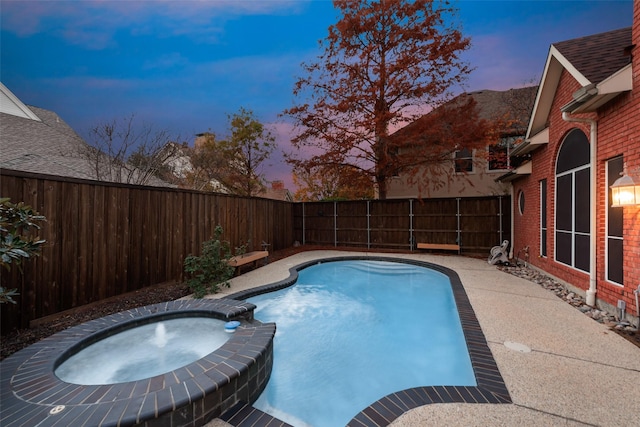 pool at dusk with an in ground hot tub