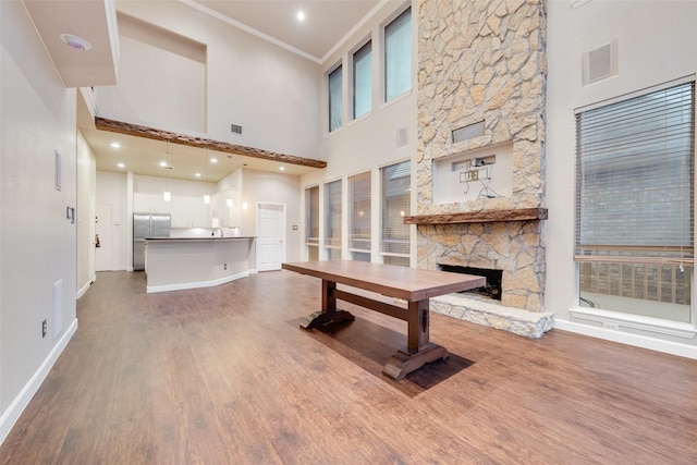 unfurnished living room with a fireplace, a towering ceiling, wood-type flooring, and ornamental molding