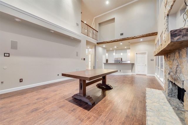 interior space featuring hardwood / wood-style floors, a stone fireplace, and a towering ceiling