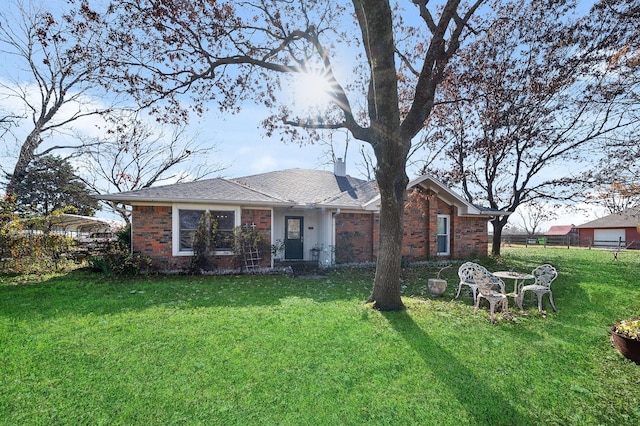 view of front of house featuring a front yard, brick siding, fence, and a chimney