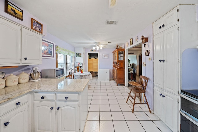 kitchen featuring visible vents, white cabinets, a peninsula, stainless steel appliances, and light tile patterned flooring