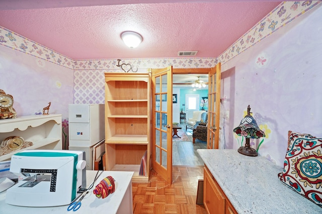 interior space with wallpapered walls, visible vents, a textured ceiling, and french doors