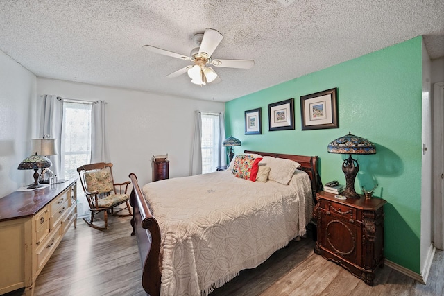 bedroom with a textured ceiling, multiple windows, a ceiling fan, and light wood-style floors