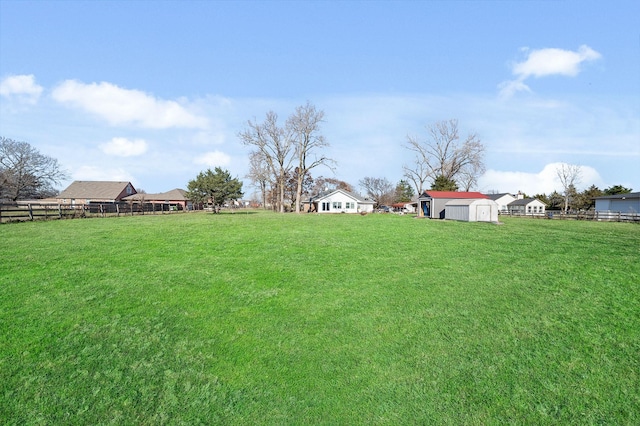 view of yard featuring an outbuilding, a shed, and fence