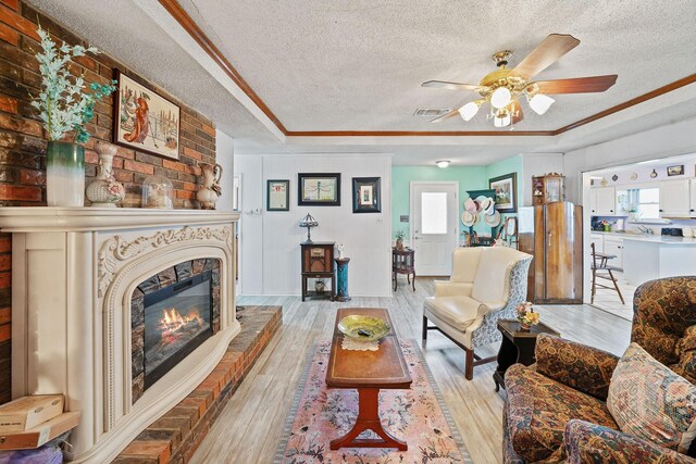 living room with a fireplace, a textured ceiling, and light wood-type flooring