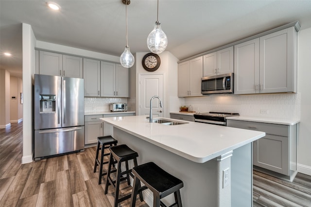 kitchen with sink, stainless steel appliances, a center island with sink, and gray cabinetry