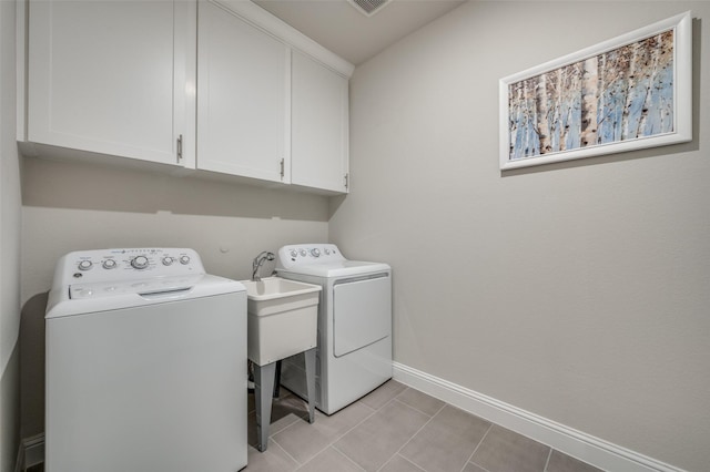 clothes washing area with cabinets, washing machine and dryer, and light tile patterned floors