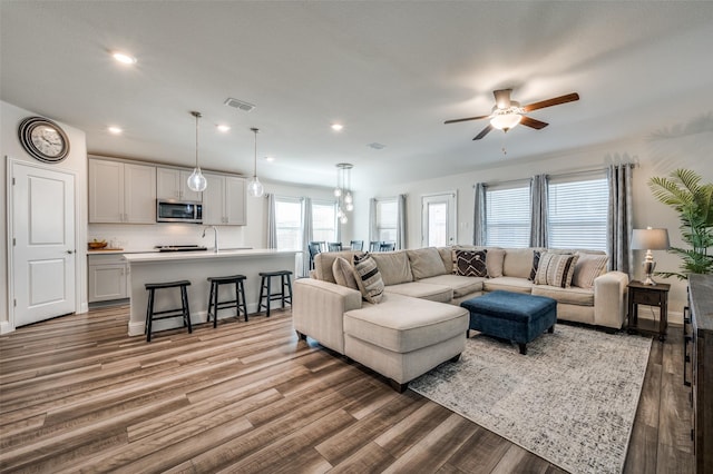 living room featuring ceiling fan, sink, and hardwood / wood-style floors