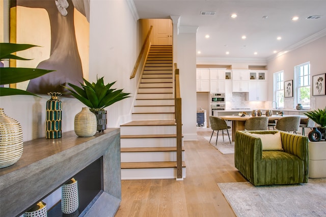 stairway with wood-type flooring and crown molding