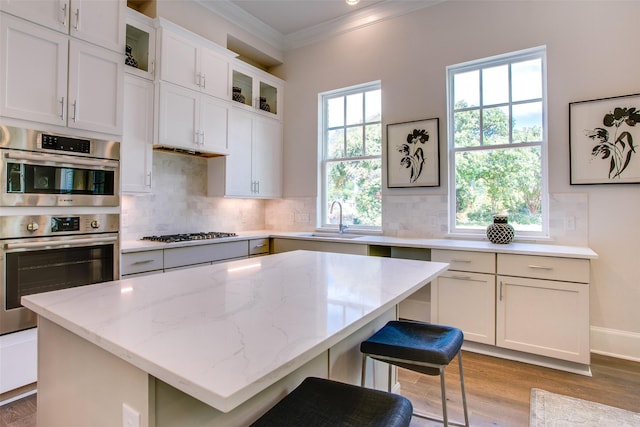 kitchen featuring light stone countertops, sink, white cabinets, and a kitchen island