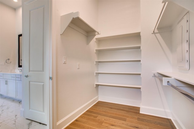 walk in closet with light hardwood / wood-style flooring