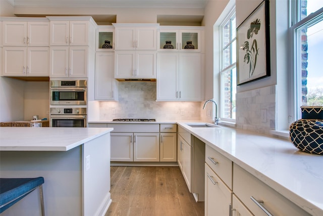 kitchen with appliances with stainless steel finishes, tasteful backsplash, sink, light hardwood / wood-style flooring, and white cabinets