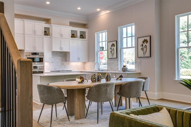 kitchen with crown molding, plenty of natural light, white cabinets, and light hardwood / wood-style floors