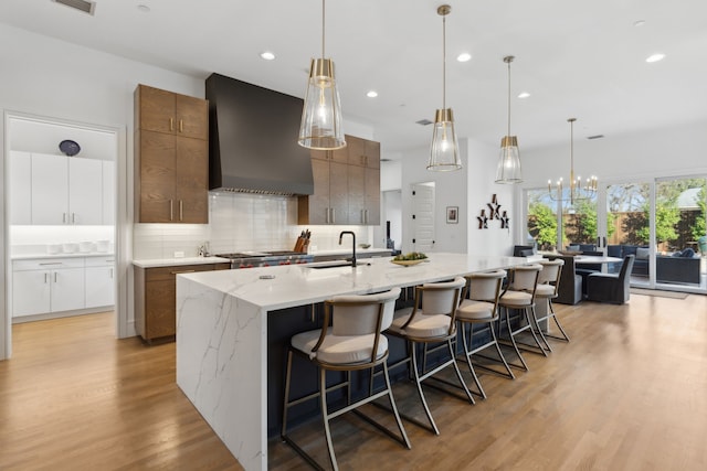 kitchen with a spacious island, decorative backsplash, hanging light fixtures, and custom range hood