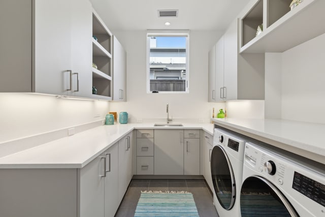 clothes washing area featuring sink, washer and clothes dryer, cabinets, and dark tile patterned floors