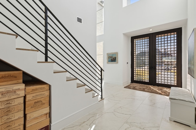 entryway featuring french doors and a towering ceiling