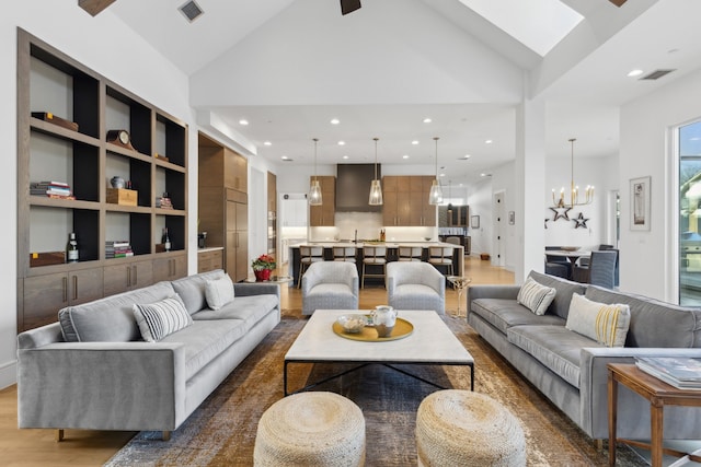 living room with high vaulted ceiling, dark hardwood / wood-style floors, built in features, and an inviting chandelier