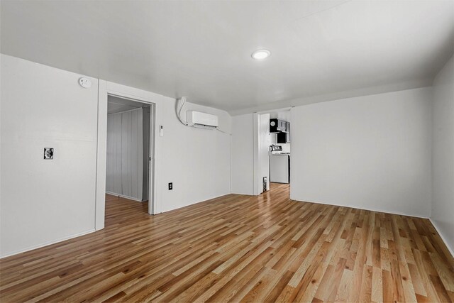 basement featuring light hardwood / wood-style floors and a wall mounted AC