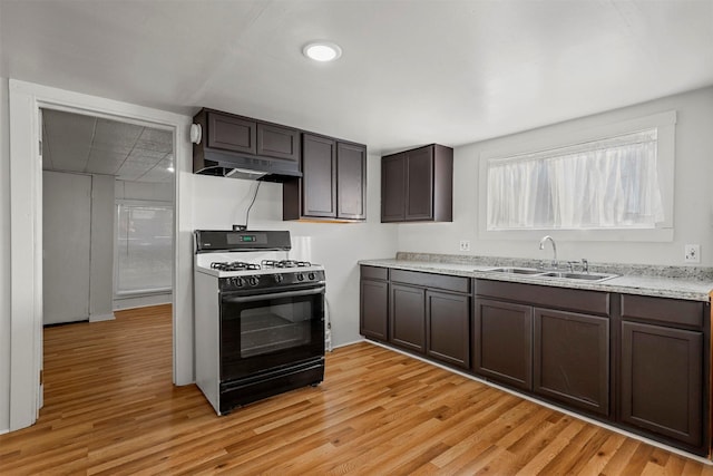 kitchen featuring black gas stove, light wood-type flooring, dark brown cabinets, and sink