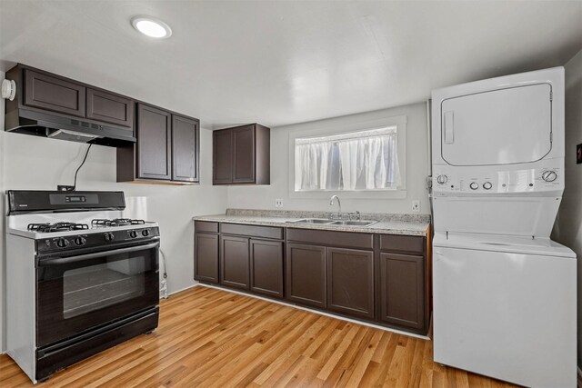 kitchen featuring stacked washer / drying machine, sink, dark brown cabinetry, and black gas range oven