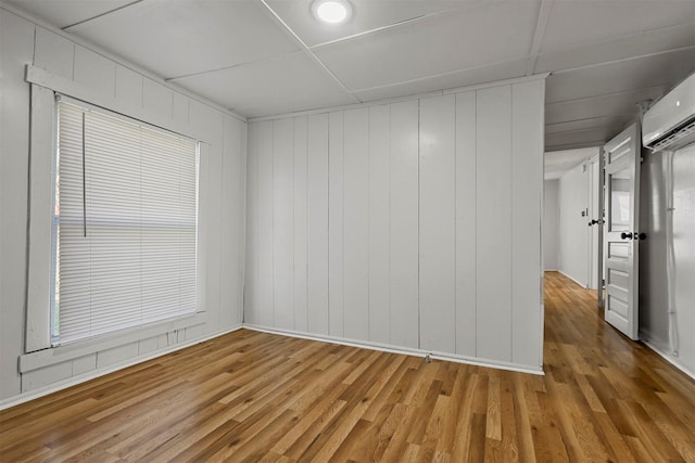 empty room featuring wood-type flooring and an AC wall unit