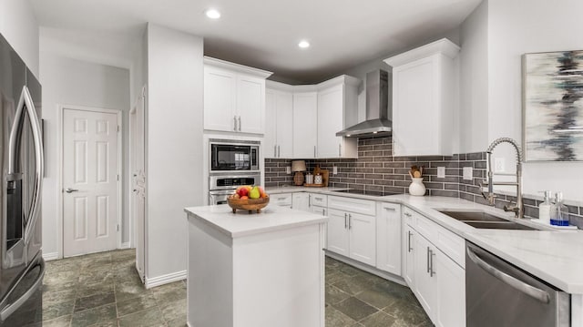 kitchen featuring white cabinetry, appliances with stainless steel finishes, a center island, wall chimney exhaust hood, and sink