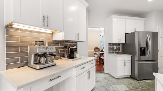 kitchen with stainless steel refrigerator with ice dispenser, white cabinetry, tasteful backsplash, and light stone countertops