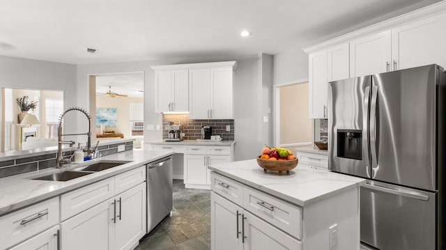 kitchen featuring backsplash, sink, white cabinetry, light stone countertops, and appliances with stainless steel finishes