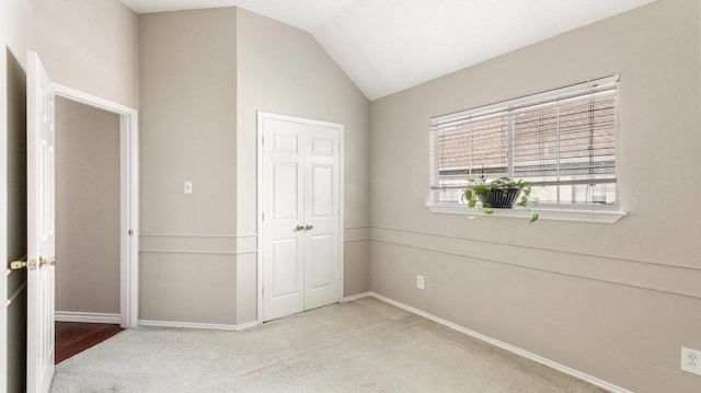 unfurnished bedroom with light colored carpet, a closet, and vaulted ceiling