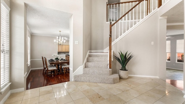 stairs with tile patterned flooring, a notable chandelier, ornamental molding, and a textured ceiling