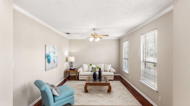 living room with ceiling fan, a textured ceiling, ornamental molding, and light hardwood / wood-style flooring