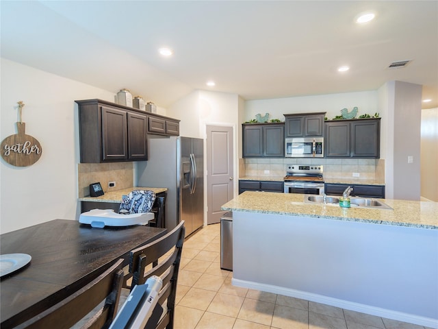 kitchen with light tile patterned floors, backsplash, stainless steel appliances, and dark brown cabinetry