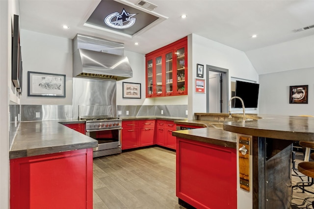 kitchen featuring sink, light hardwood / wood-style flooring, high end range, kitchen peninsula, and wall chimney exhaust hood