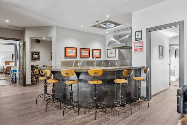 bar featuring wall chimney exhaust hood