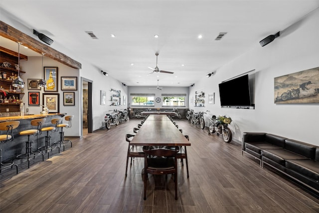 dining space featuring dark hardwood / wood-style flooring, ceiling fan, and bar area