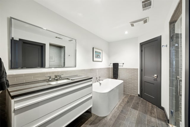 bathroom with tile walls, vanity, and independent shower and bath