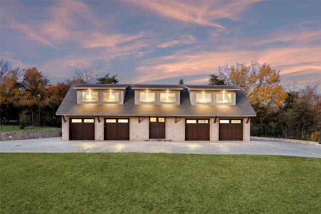 garage at dusk featuring a lawn