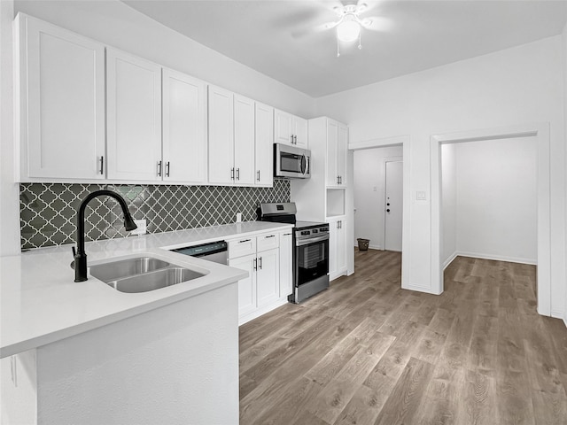 kitchen with white cabinets, sink, decorative backsplash, light wood-type flooring, and appliances with stainless steel finishes